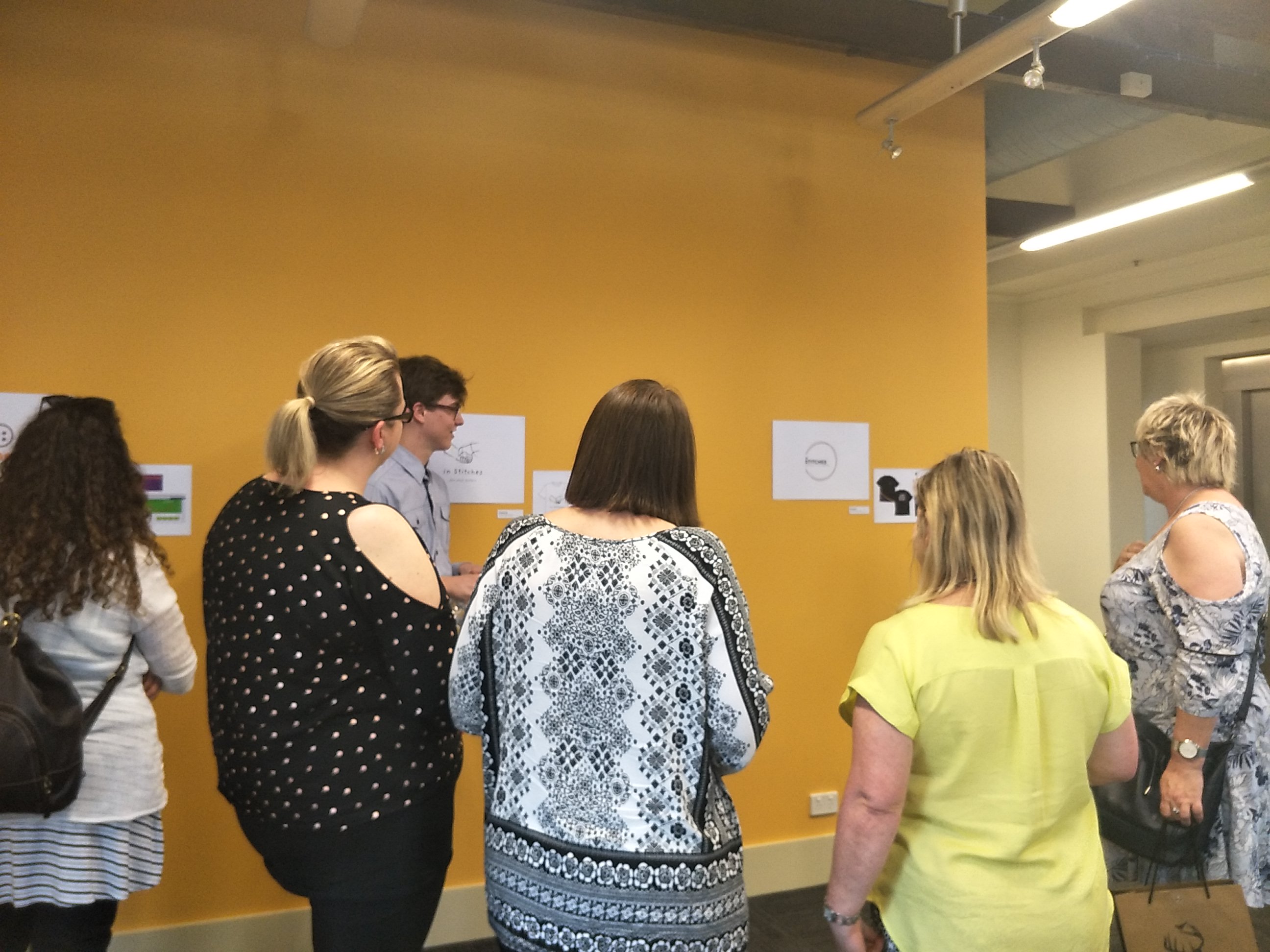 People looking at student work displayed in the Freerange Future office space.