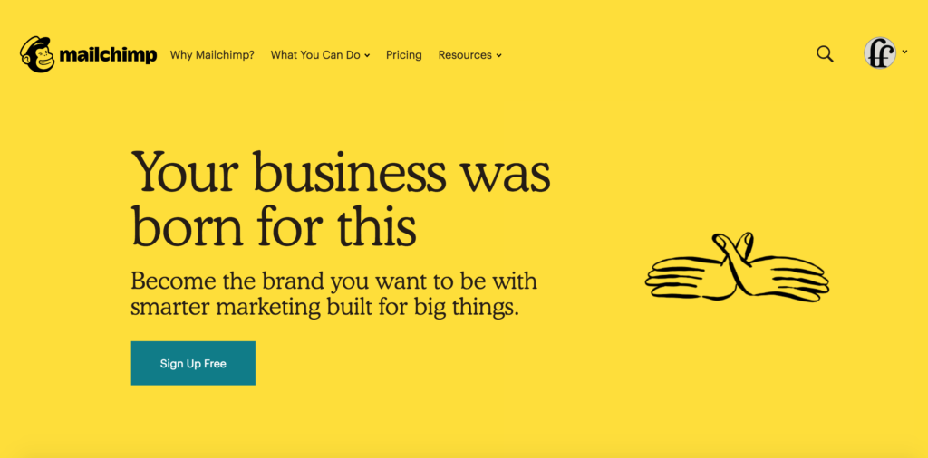 The Mailchimp home page. The tagline 'Your business was born for this' is visible, followed by the subtitle, 'Become the brand you want to be with smarter marketing built for big things.' and a CTA button, 'sign up for free' below. There is a sketch of a to hands mimicking a bird with spreaded wings to the right of the text.