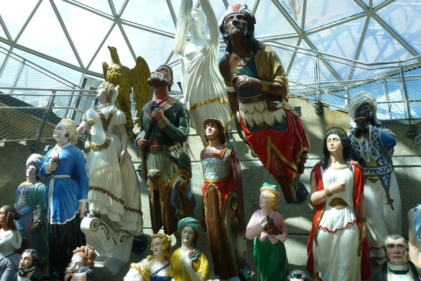 Lots of sculptures of people, many holding a hand to their chest and looking upwards